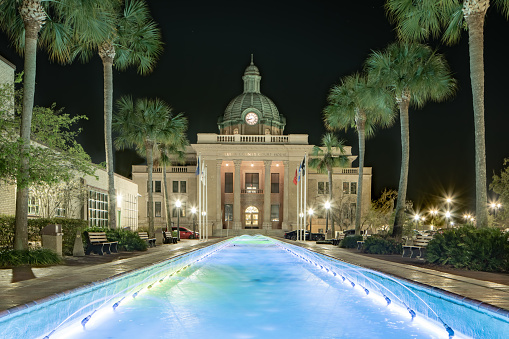 Evening photo of the historic Volusia County Courthouse and fountain pool in DeLand, Florida.