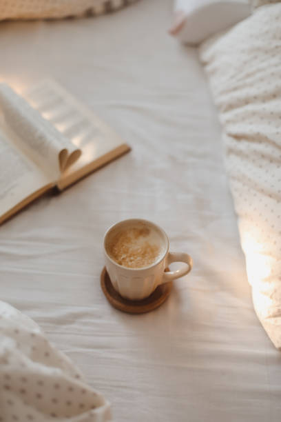 istock Cozy morning composition with a coffee cup and a book with pages folded into a heart shape in bed 1471966558