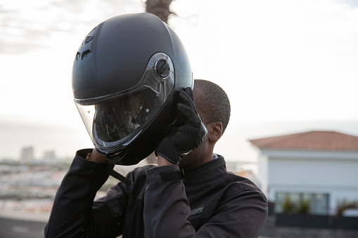 A motorcyclist puts on his helmet before setting off, road safety concept