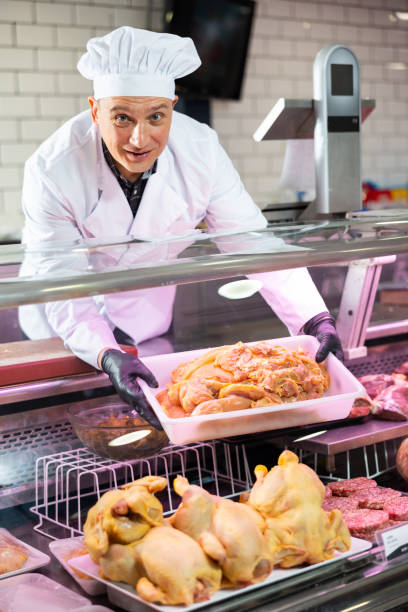 istock Butcher placing tray with raw chicken fillet on display 1471970697