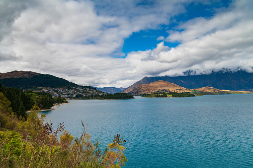 Scenic view of Lake Wakatipu and Queenstown. In the background early season snow is seen falling on The Remarkables mountain range.