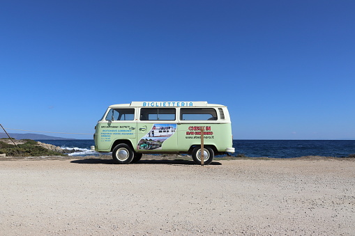 Sardinia, Italy: October 10, 2021: Green classic van labeled for ticket sales on a beach in Sardinia, Italy. Vertical image.