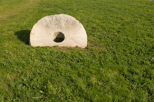 Stone wheel of an old mill on green grass in Plencia