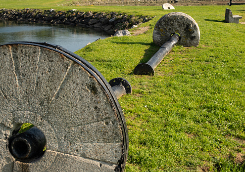 Iron axes and stone wheels of an old mill on the grass of a park in Plencia