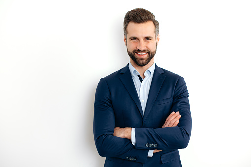 Portrait of handsome mid adult man wearing grey suit and white shirt, looking up and smiling. Studio shot of male entrepreneur against grey background.