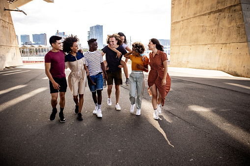 United group of multiracial young friends walking on city street - Millennial diverse best friends enjoying free time together in summer holidays
