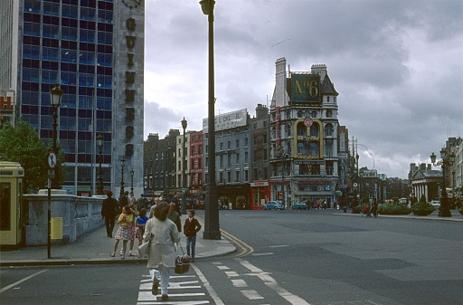Dublin, Ireland, 1970. Street scene at O'Connell Bridge. Furthermore: pedestrians, buildings and advertising signs.