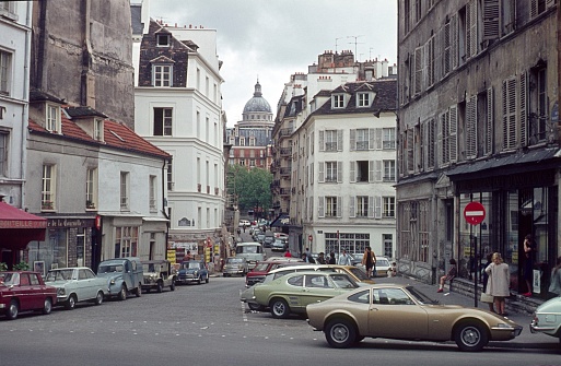 Paris, Il de France, France, 1976. Street scene with locals, buildings, shops and vehicles in the 5th arrondissement of Paris looking towards the Panthéon.