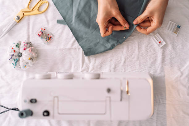 lady fixes fabric with needles in front of a sewing machine - seam needle textile industry thread imagens e fotografias de stock