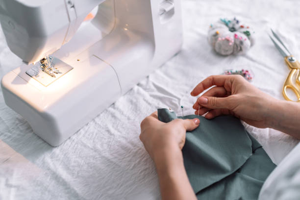 istock Lady fixes fabric with needles in front of a sewing machine 1471978913