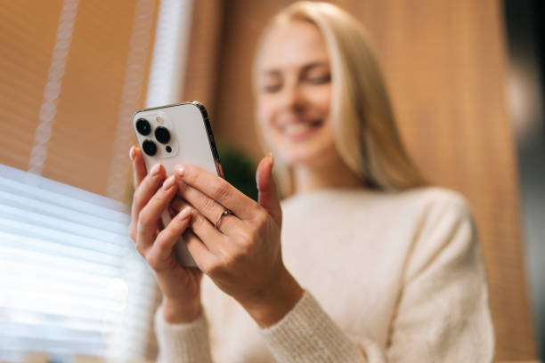 istock Selective focus shot of smiling young woman relaxing on comfortable sofa using smartphone chatting in social networks, watching funny videos at home. 1471979234