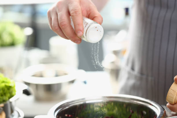 istock Chef adds salt from salt bowl to dish closeup 1471988631