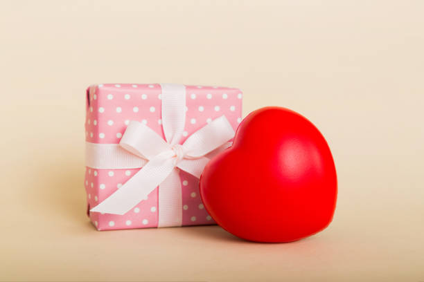 istock gift box with red bow and red heart on colored background. Perspective view. Flat lay 1471989950