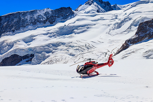 Red helicopter landed at Jungfrau mountain in Bernese Oberland, Switzerland