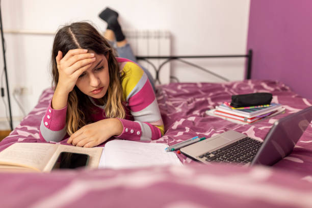 istock Caucasian girl lying on bed and doing school homework. 1471990421