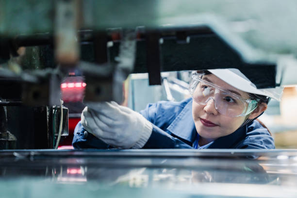 A female technician maintaining and inspecting machinery stock photo