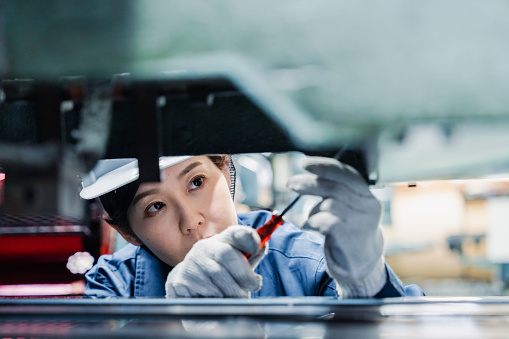 A female technician maintaining and inspecting machinery