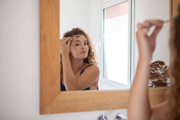 istock Young woman combing her eyebrows in front of the mirror 1471990971