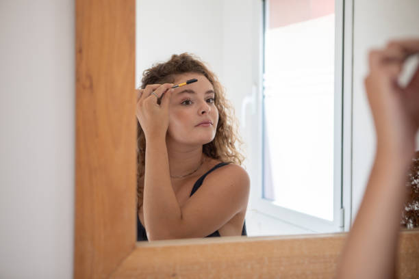 istock Young woman combing her eyebrows in front of the mirror 1471990973
