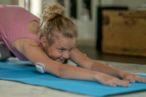 Diabetes and Fitness A young girl with Diabetes is seen balancing life with her disease as she tires to meditate at home while maintaining her blood sugar levels. exercise diabetes stock pictures, royalty-free photos & images