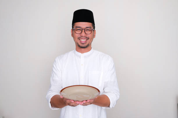 istock Moslem Asian man smiling and showing empty dinner plate 1471996288