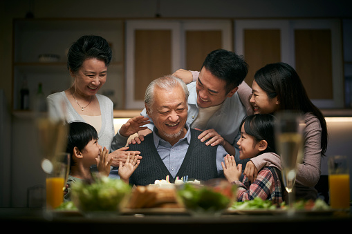 happy three generation asian family celebrating grandpa's birthday at home