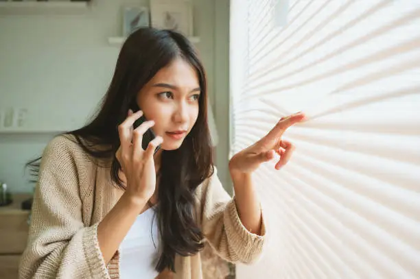 Young asian woman using mobile smartphone and looking at outside window