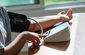 Arms of woman measuring blood pressure at home