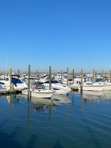 White boats docked at a marina and their reflection in Long Island,