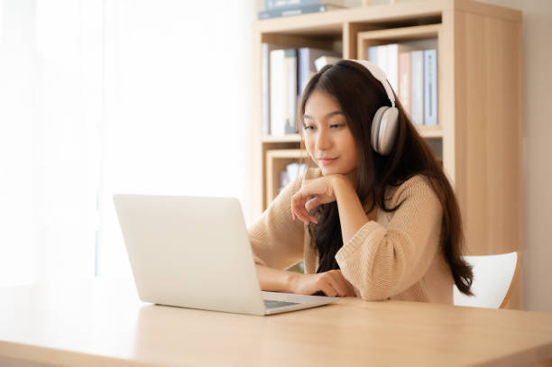 istock Young asian woman wearing headset while working on computer laptop at house. Work at home, Video conference, Video call, Student learning online class 1472001897