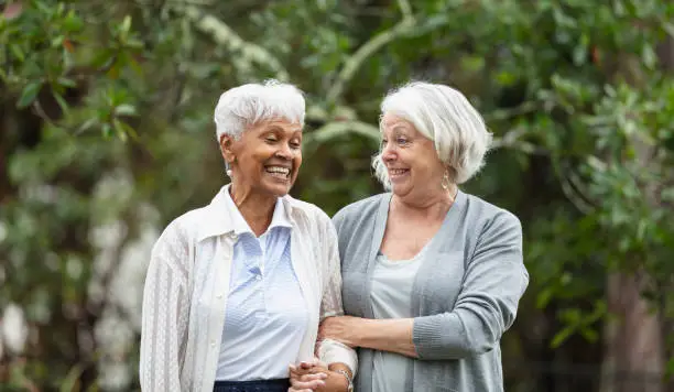 Photo of Senior women walking, talking in back yard, smiling