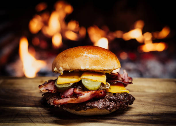 istock Smashed Cheeseburger on a wooden table in front of a fireplace. 1472003469