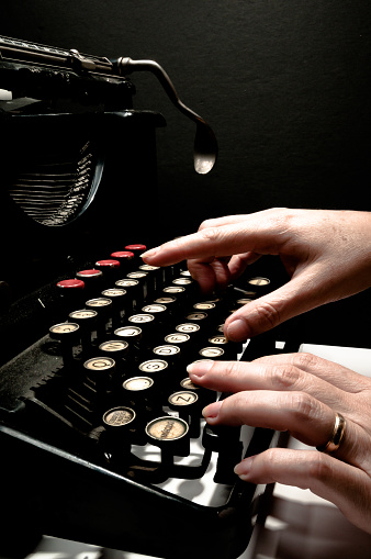 Woman's hands typing on a antique typewriter, interesting piece, mix of art, culture and historical engineering.