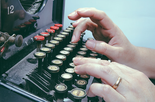 Woman's hands typing on a antique typewriter, interesting piece, mix of art, culture and historical engineering.