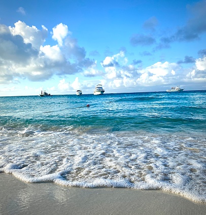 Tiny boats in the distance of the coastline and Caribbean beach with turquoise waters,