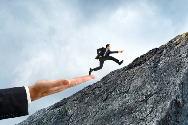 istock Businessman Using A Helping Hand To Reach His Goal 1472006876