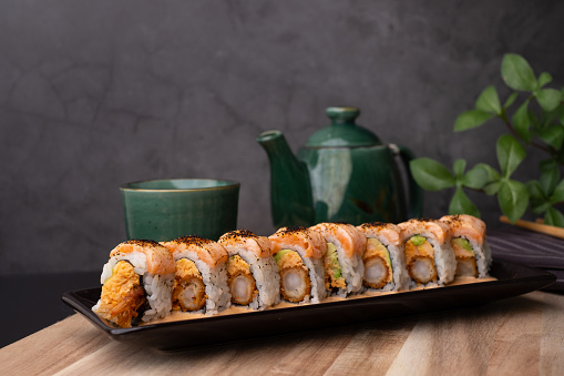 tempura sushi roll topped with seared salmon and serve with hot tea. Japanese traditional dishes and healthy food.