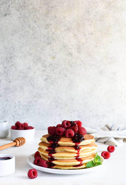 istock Homemade pancakes with raspberries and jam for breakfast on a white background 1472014901
