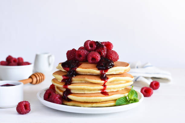 istock Homemade pancakes with raspberries and jam for breakfast on a white background 1472014904