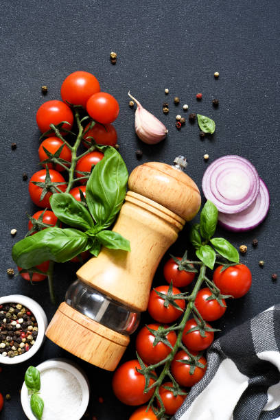 istock Pepper grinder, basil, spices and vegetables on a kitchen black table with space for text. Food ingredients. 1472015823