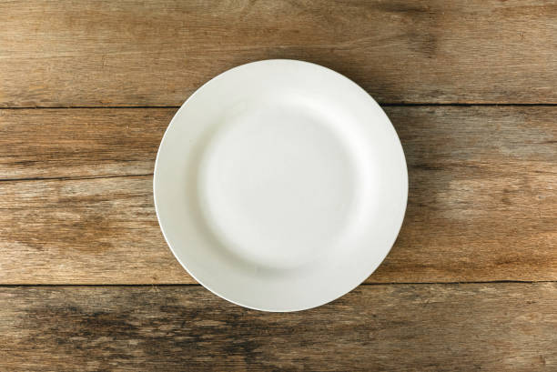 istock Top view of empty white plate on a wooden background. Flat lay, copy space. 1472016006