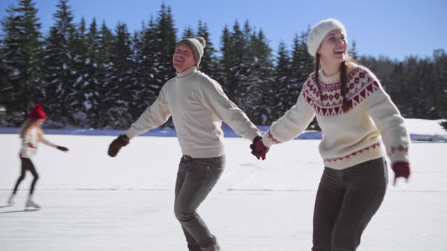 SLO MO TS Man and woman holding hands and smiling while ice skating on a lake