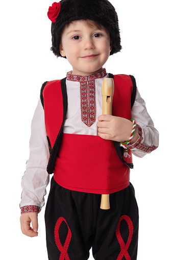 Bulgarian boy in traditional ethnic folklore costume, martenitsa and wooden flute, Bulgaria