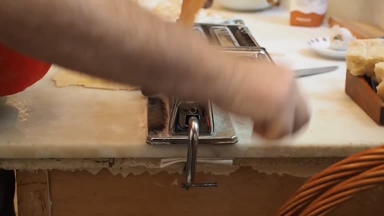Home kitchen process of making home-made dumplings, ravioli or pelmeni with pumpkin filling using mold or pasta maker. Ready for cooking raviolis on marble table board,senior woman couple bonding.