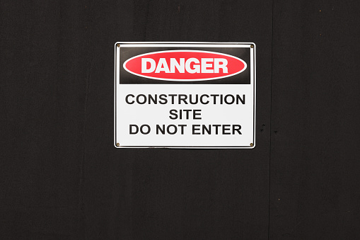 Danger, construction site sign on a black wall.