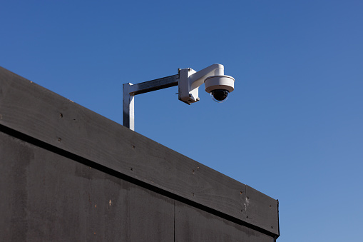 Long pole with security camera against a blue sky.