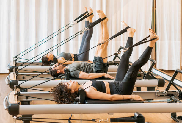 Group of people having pilates workout on equipment Full body of concentrated people in activewear doing exercises on pilates equipment during workout in gym pilates stock pictures, royalty-free photos & images