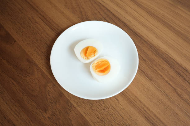 istock Sliced Boiled egg in white ceramic plate on wooden table. 1472028933