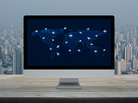 Flight routes airplanes connection and world map on computer screen on wooden table over office building tower and skyscraper, Business airplane transportation network concept, Elements of this image furnished by NASA