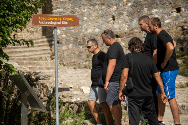 Group of people visiting archeological site and remains of ancient Sparta city located on Peloponnese peninsula, south Greece. They are reading information sign.